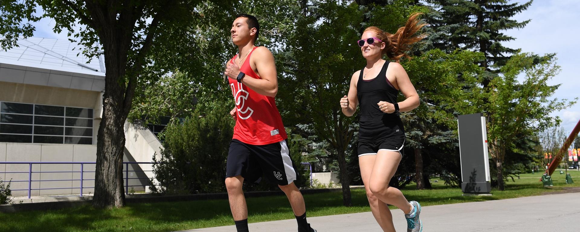 Two people wearing smart watches and running on UofC campus 