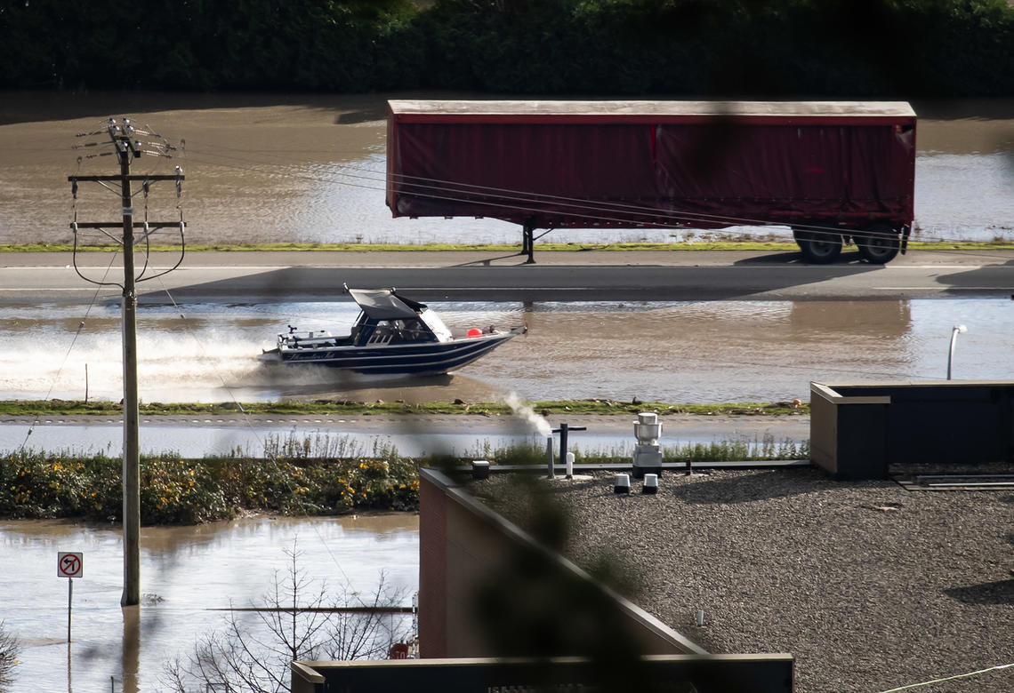 A boat travels along the Trans-Canada Highway past an abandoned transport trailer in a flooded area of Abbotsford, B.C. 