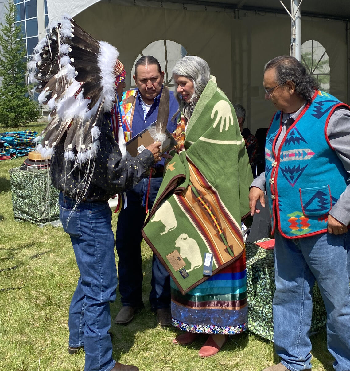 Michelle Scott receives an eagle feather, medallion, and Pendleton blanket from Elders during the UCalgary Indigenous graduation celebration.