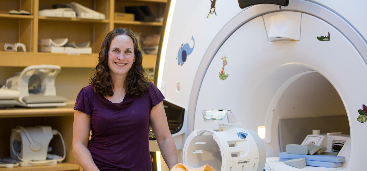 Dr. Catherine Lebel standing in front of a MRI at the Alberta Children's Hospital