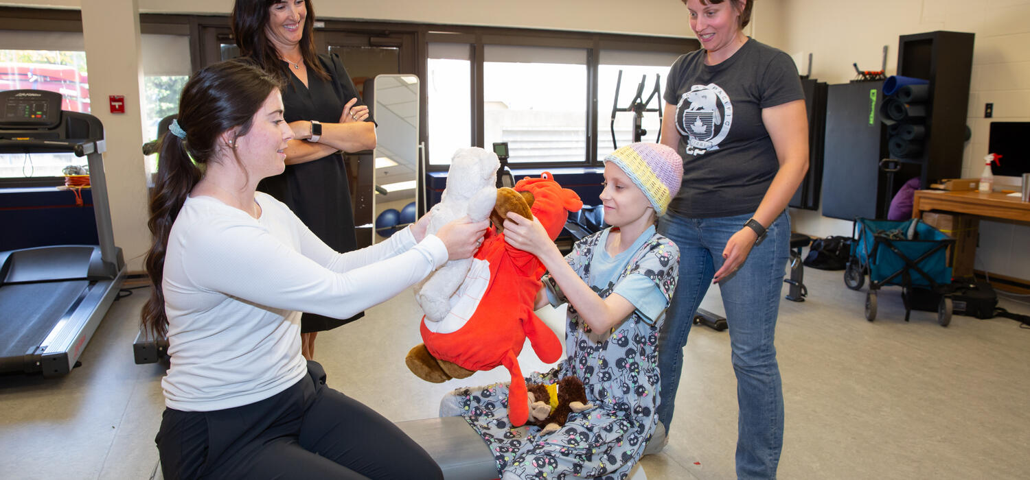 With IMPACT study participant Mira, 10, are Emma McLaughlin, seated, Nicole Culos-Reed, left, and Bridget Penney, right.