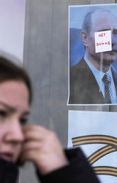 A woman walks past a ‘No War’ sign stuck on a portrait of Russian President Vladimir Putin in St. Petersburg, Russia, on March 29.