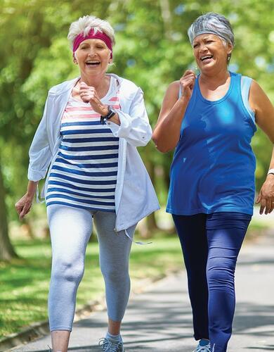 Older women walking together and laughing on a path in the summer