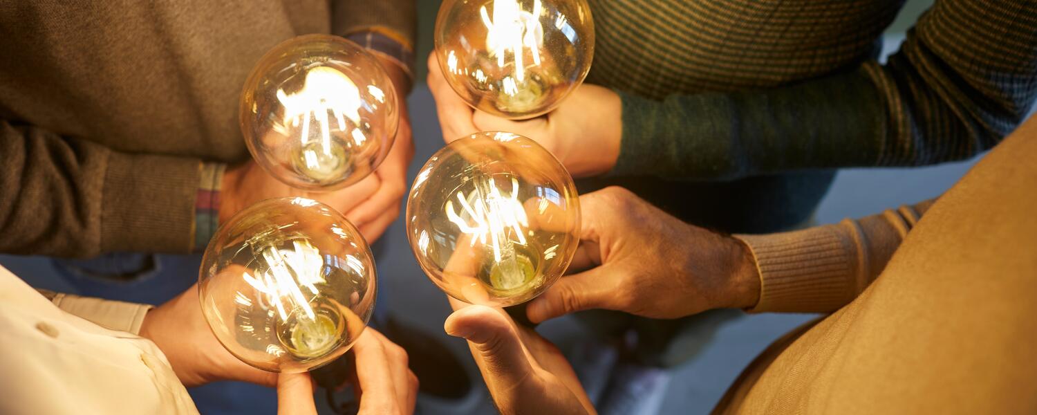 group of people holding lightbulbs 