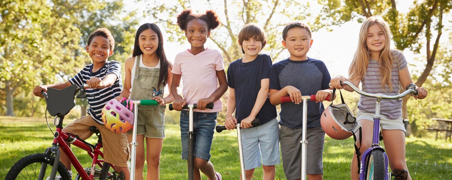 kids standing outside with scooters and bikes