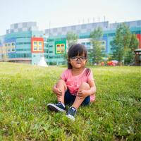 photo of little girl, Everly Tram, sitting in the grass outside Alberta Children's hospital 